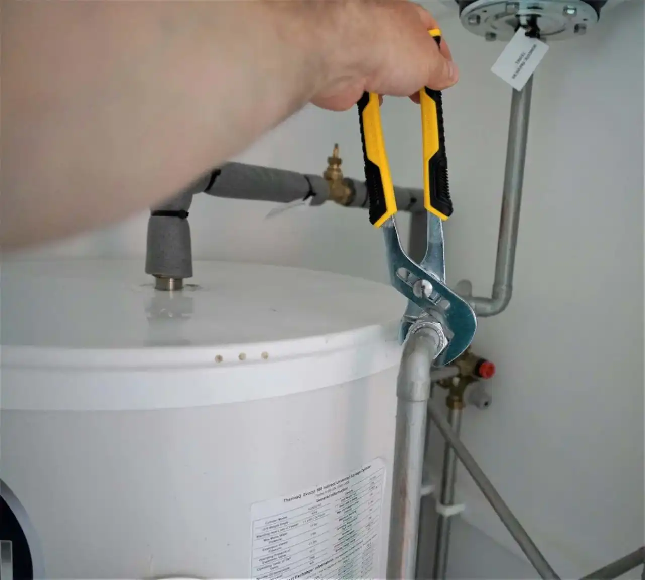 Installateur raccordant un équipement de production d’eau chaude sanitaire