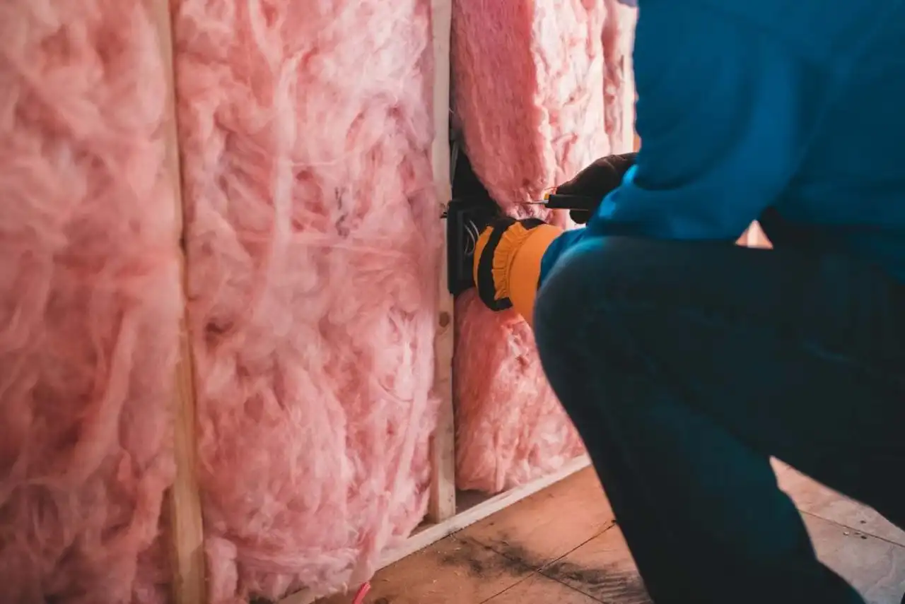 Ouvrier intervenant sur un mur en cours de rénovation, avant la pose de l’isolant