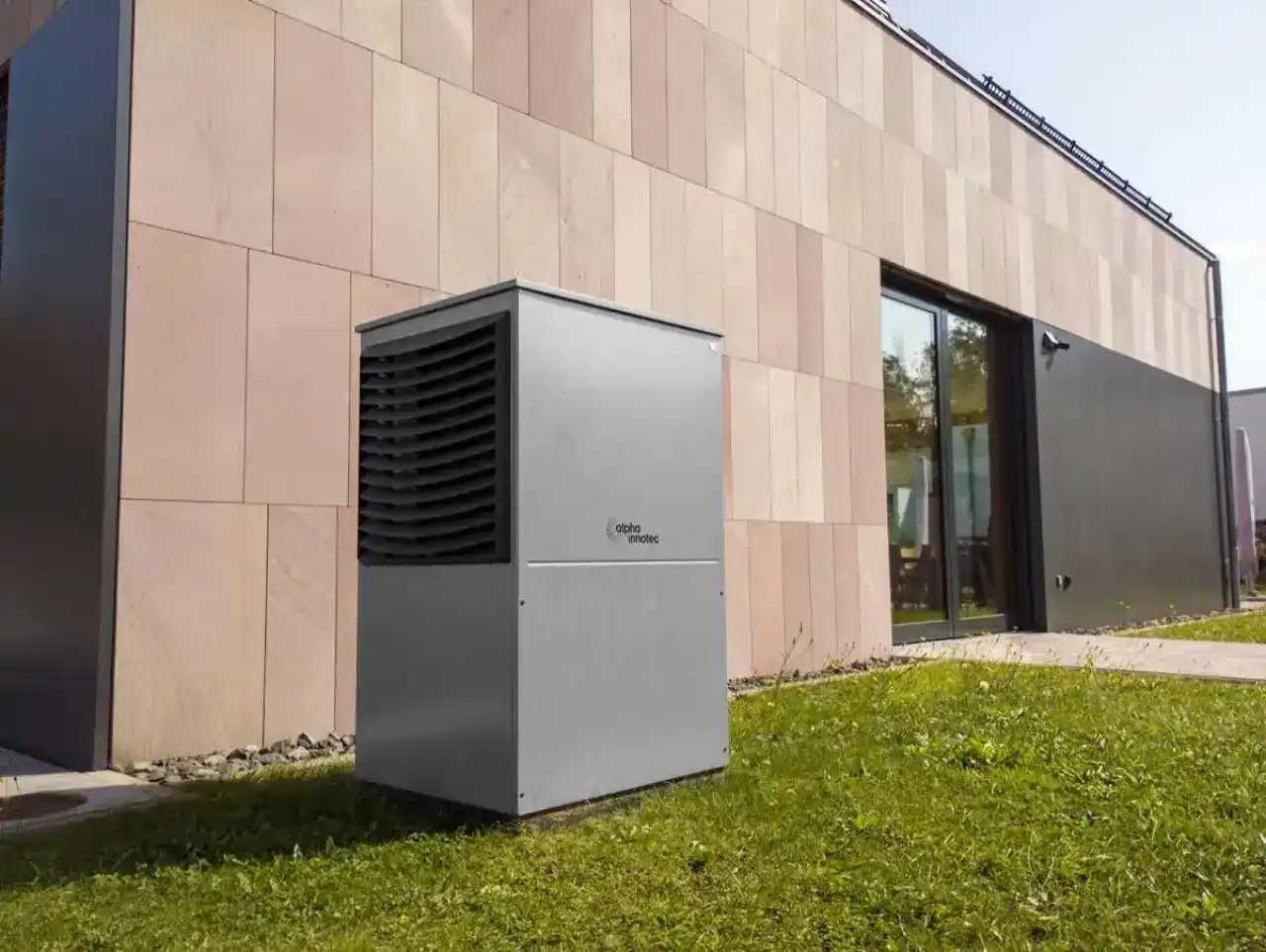 Unité extérieure d’une pompe à chaleur air/eau installée au pied de la façade d’une maison contemporaine